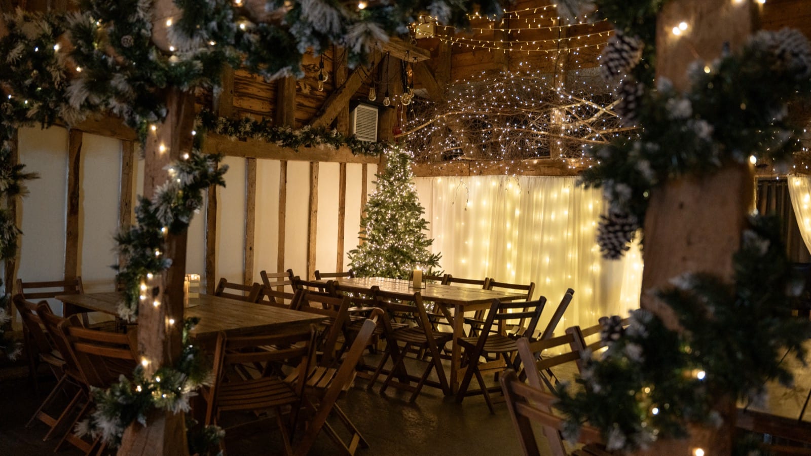 The rustic Apple Barn decorated for Christmas with a tree, garlands and a curtain of fairy lights