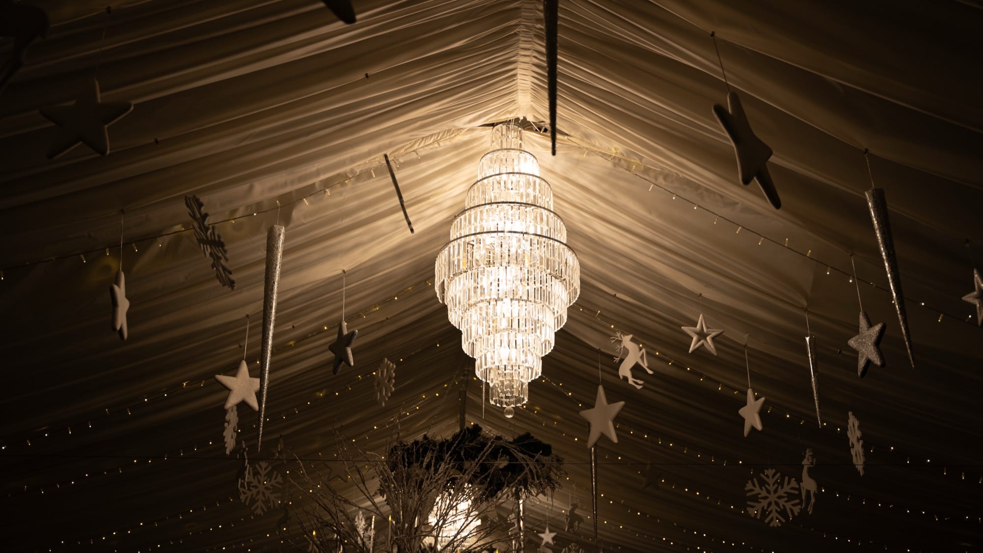 The Arboretum at Christmas, lit by chandeliers and fairy lights with stars and silver tables