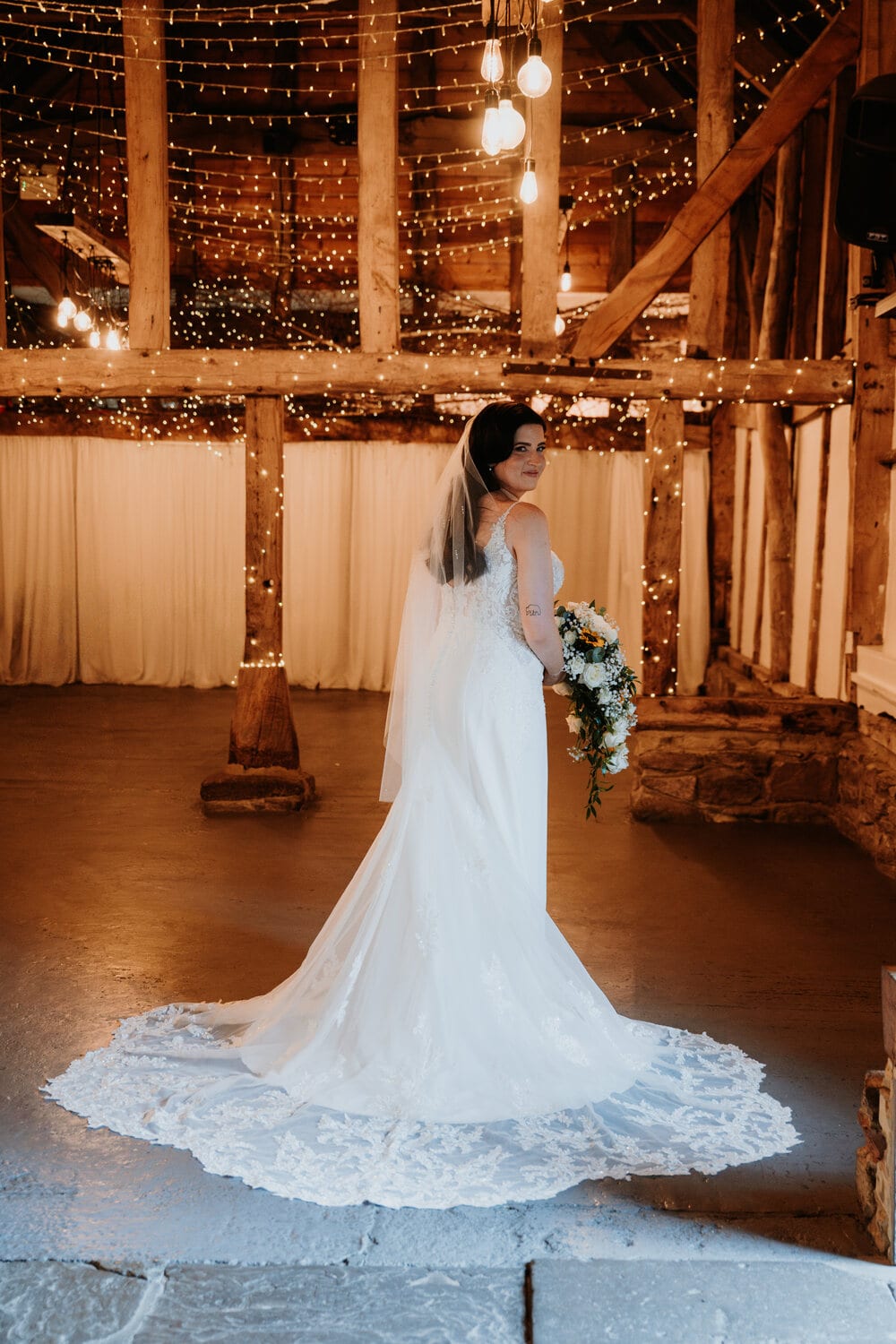 A bride walks down the aisle in the candlelit Apple Barn