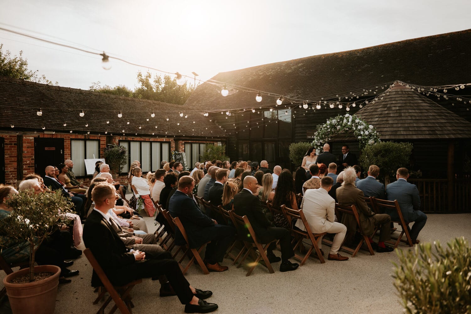 A courtyard ceremony at golden hour with guests seated