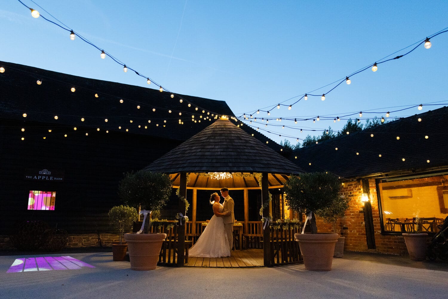 A bride in the fairy-lit courtyard at dusk