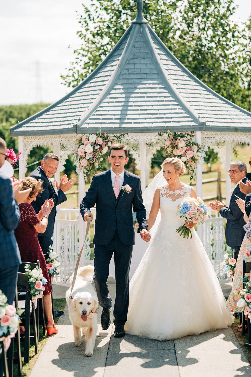 A couple walk back through confetti after an Orchard Garden ceremony