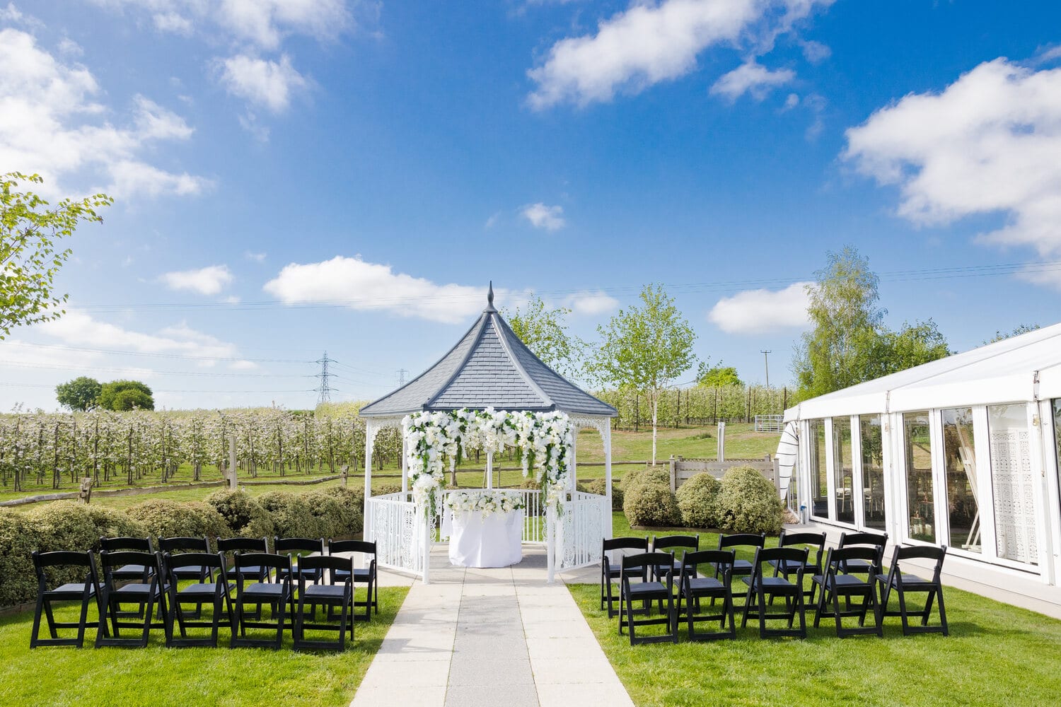 A white floral walkway leading to the Orchard Garden gazebo