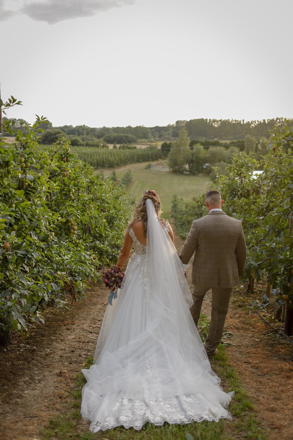 A couple walking through the orchard at The BarnYard